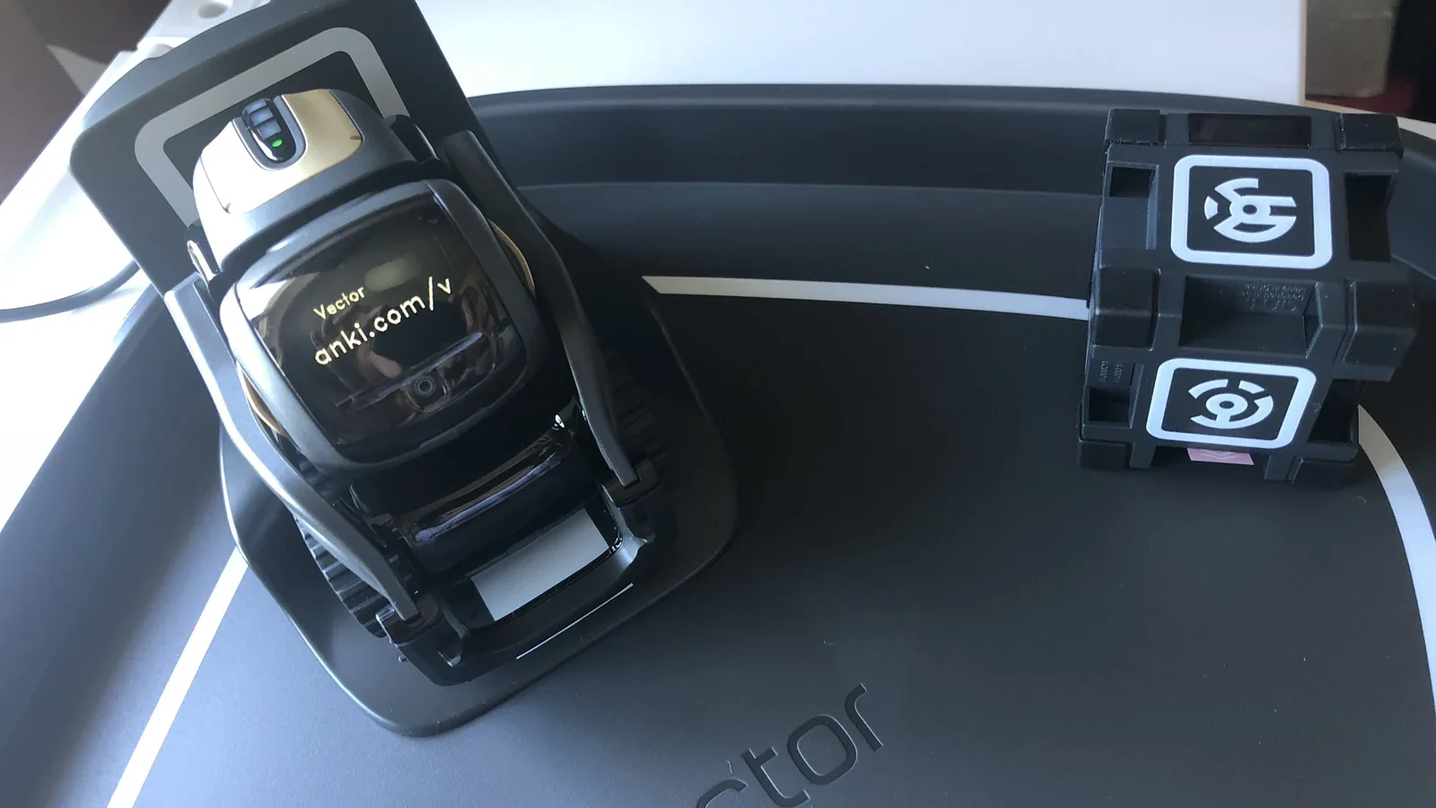 Anki Vector robot on its charging base beside its cube